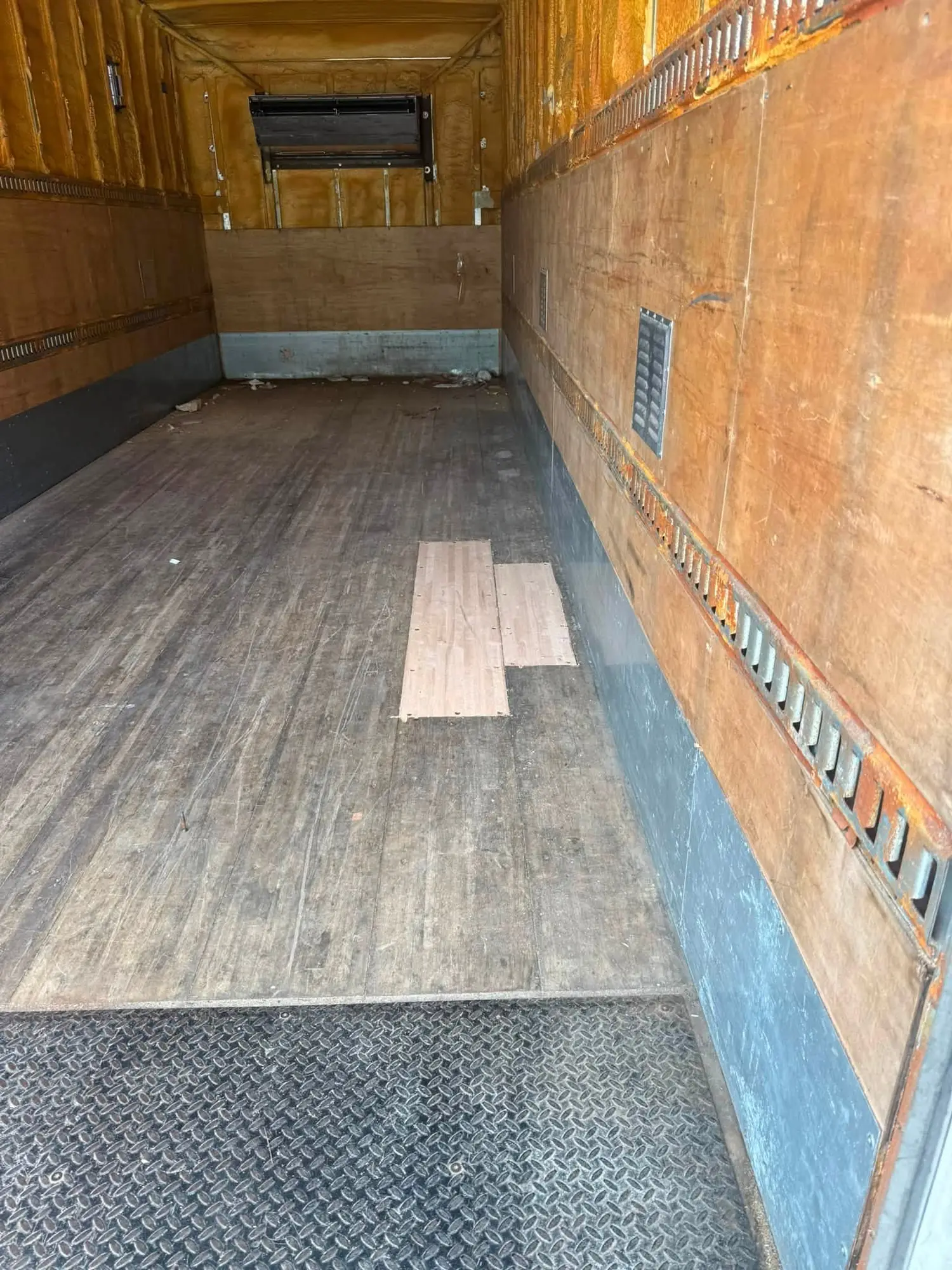New hardwood patch boards fitted flush into the worn floor of a box truck